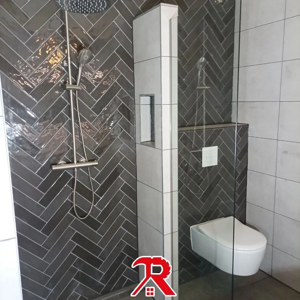 Inloopdouche met donkergrijze visgraattegels en een hangend toilet, met het R10 logo