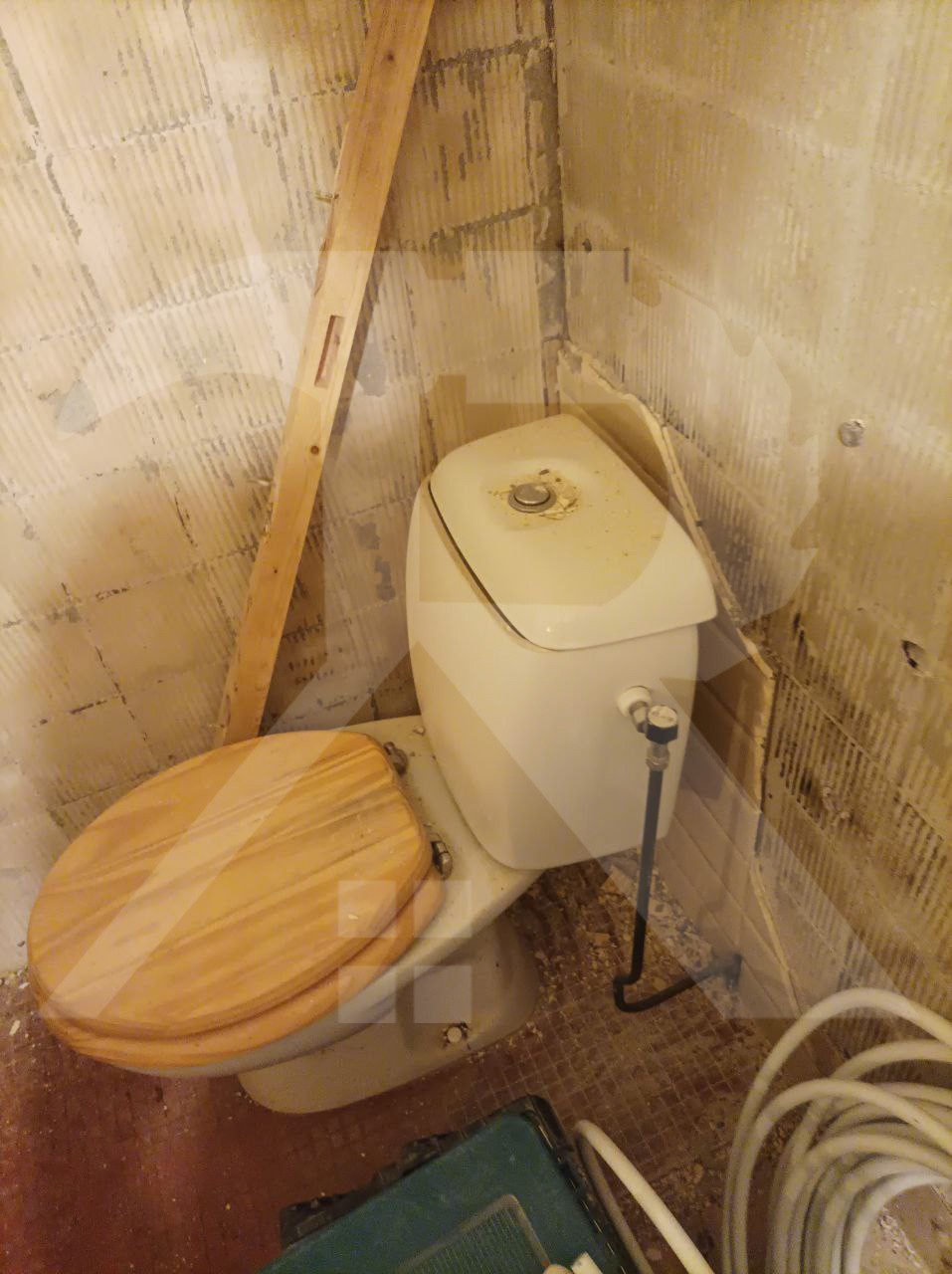 Gestripte ruimte met een oud toilet, voor de renovatie